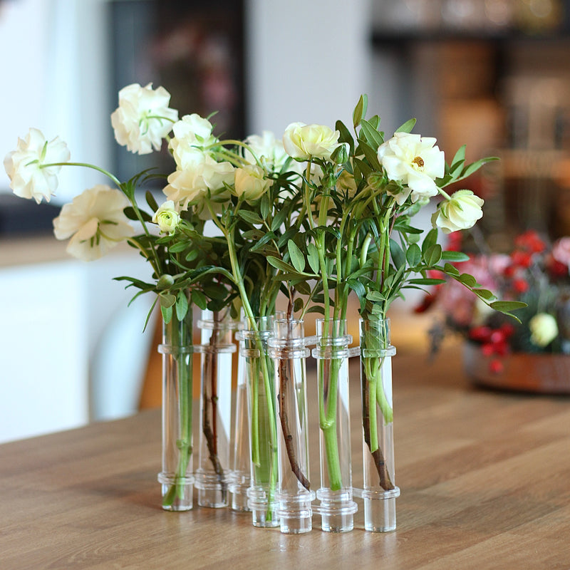 Elegante vaso Flowerflute di Hanataba che espone una composizione di rose bianche fresche su un piano di legno.