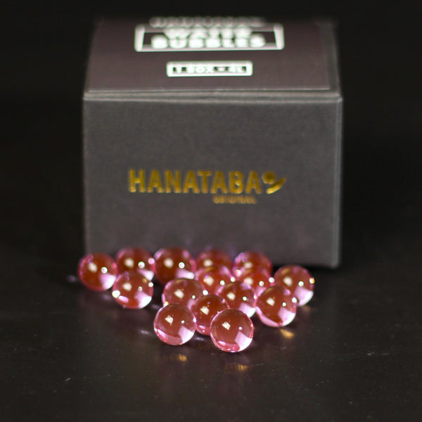 Bolle d'acqua rosa scintillanti sparse davanti a una scatola "HANATABA ORIGINAL", per creare eleganti esposizioni floreali.