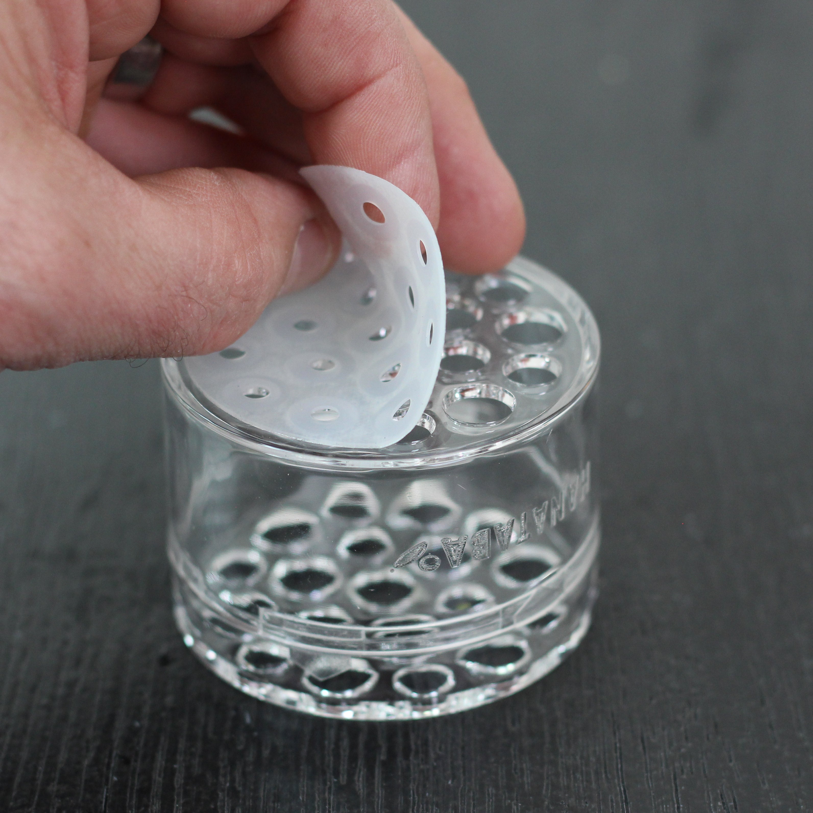 A hand placing a silicon disc on top the stem holder Hanataba crystal clear flower twister.