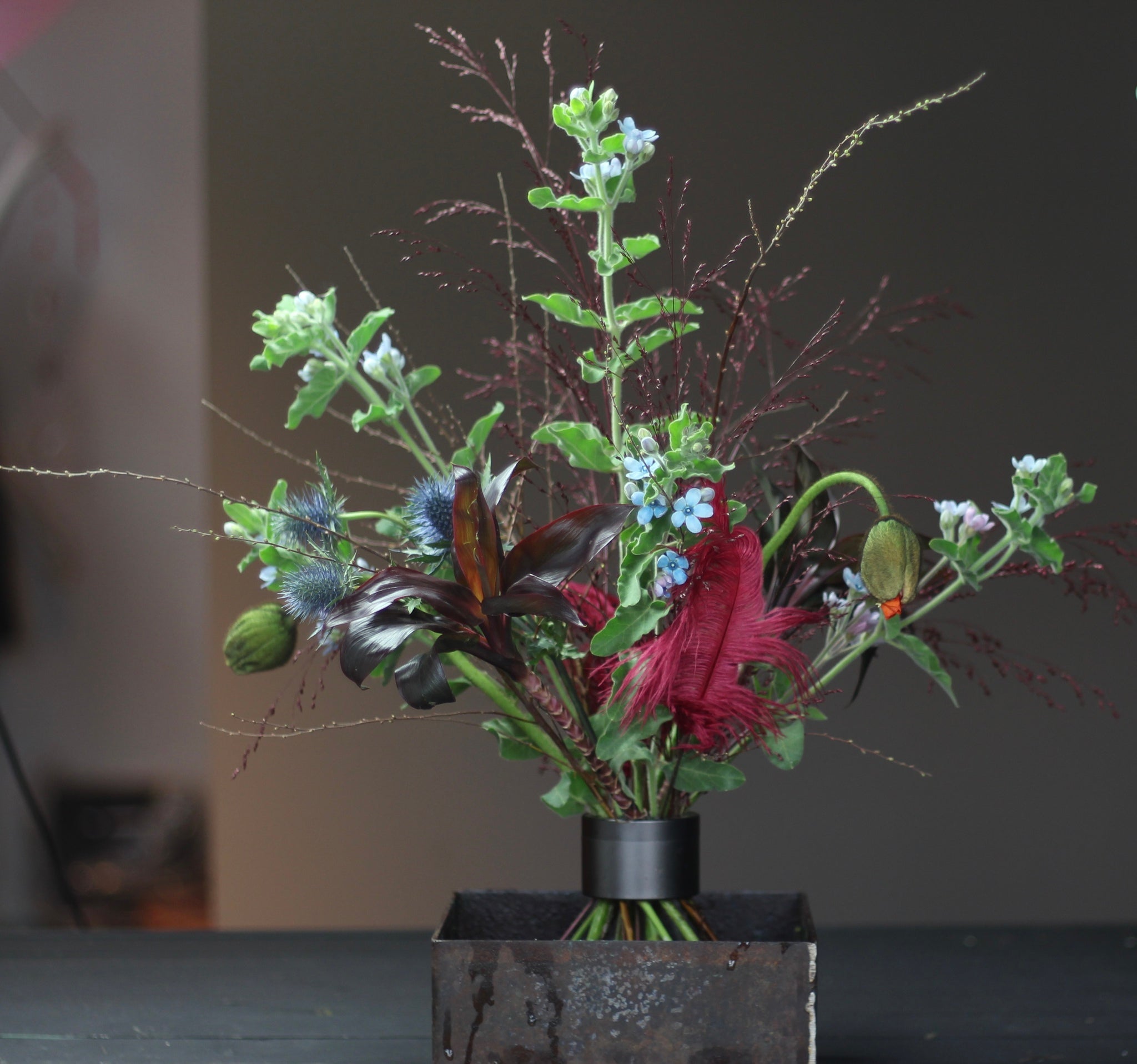 Composizione Ikebana con una varietà di fiori e fogliame fissata con un supporto a spirale Hanataba nero pece.