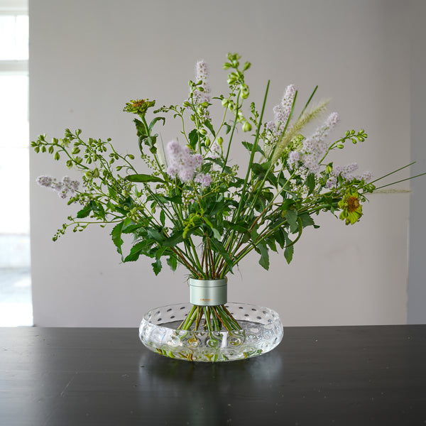 Bellissimo bouquet a spirale dai colori pastello esposto in un vaso di vetro trasparente con porta stelo di design.