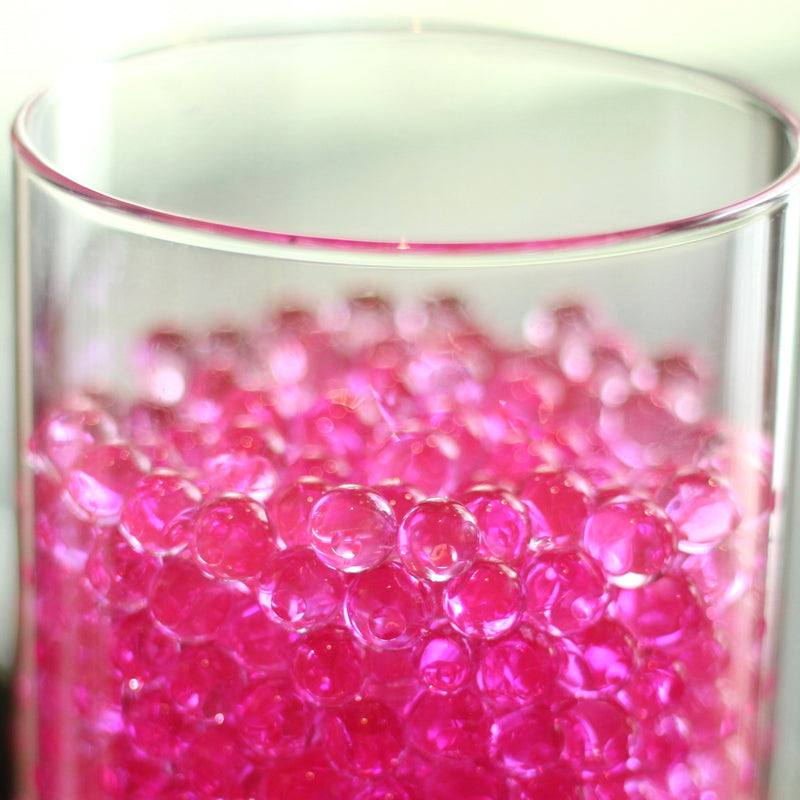 Bolle d'acqua rosa vibrante che riempiono un vaso di vetro trasparente, aggiungendo un tocco di colore alla creatività delle composizioni floreali.