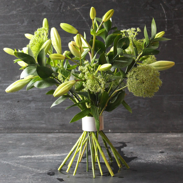 Bouquet floreale fresco verde e bianco chiuso da un twister Hanataba Pearly Silver su uno sfondo scuro.